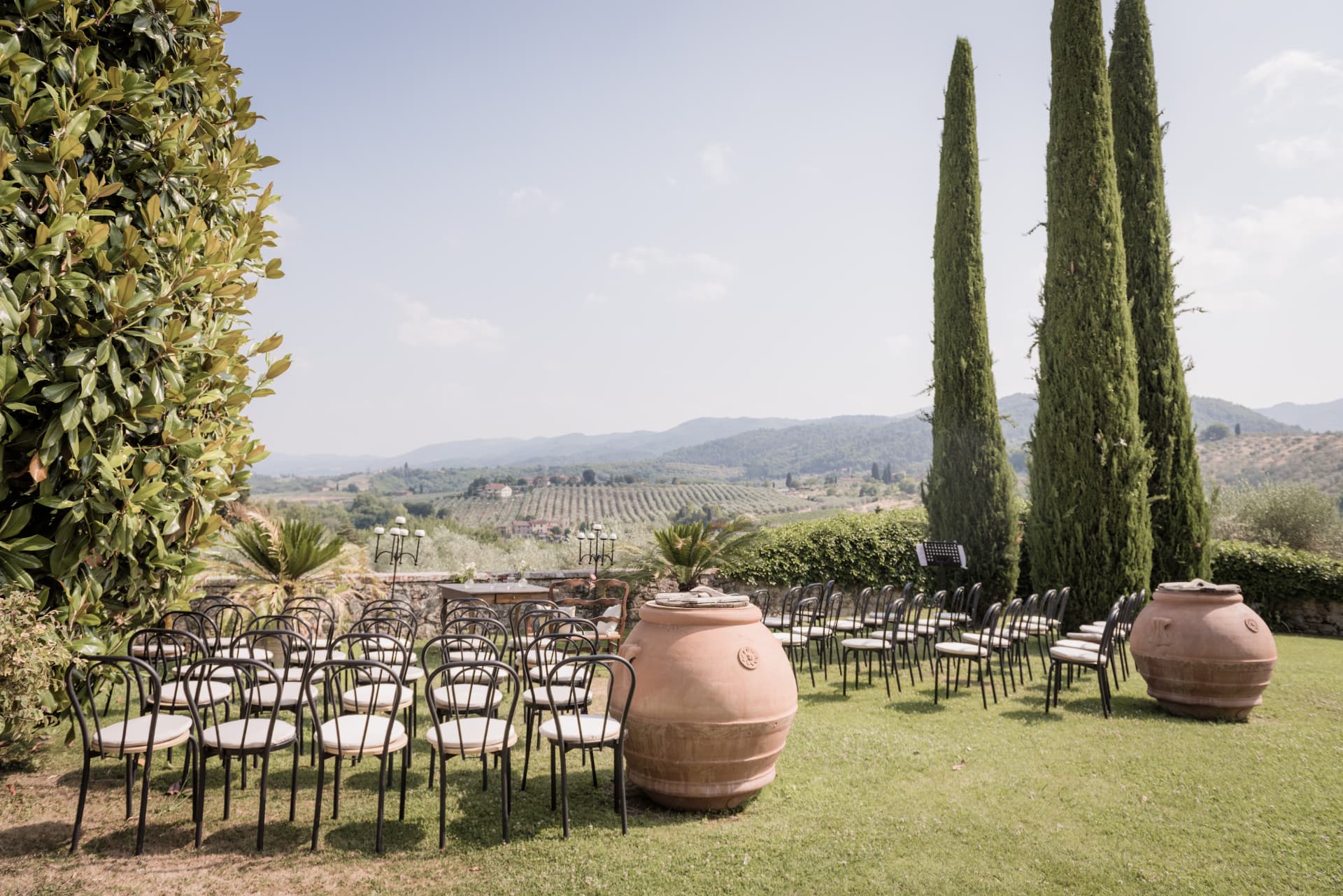 A luxury destination wedding ceremony in Italy, with elegant white chairs arranged in a sunlit landscape